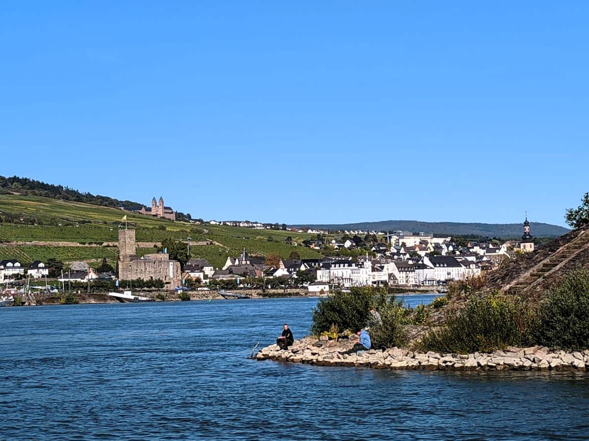 Blick über den Rhein nach Rüdesheim mit der historischen Brömserburg sanft ansteigenden Weinbergen und der Abtei St. Hildegard im Hintergrund