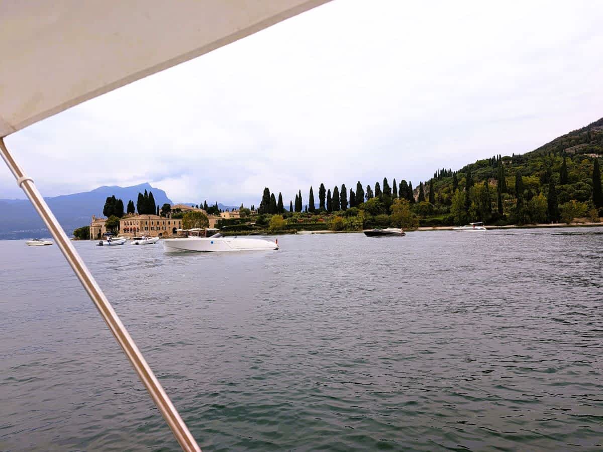 Punta San Vigilio am Gardasee mit Zypressen und Booten vor dem Ufer