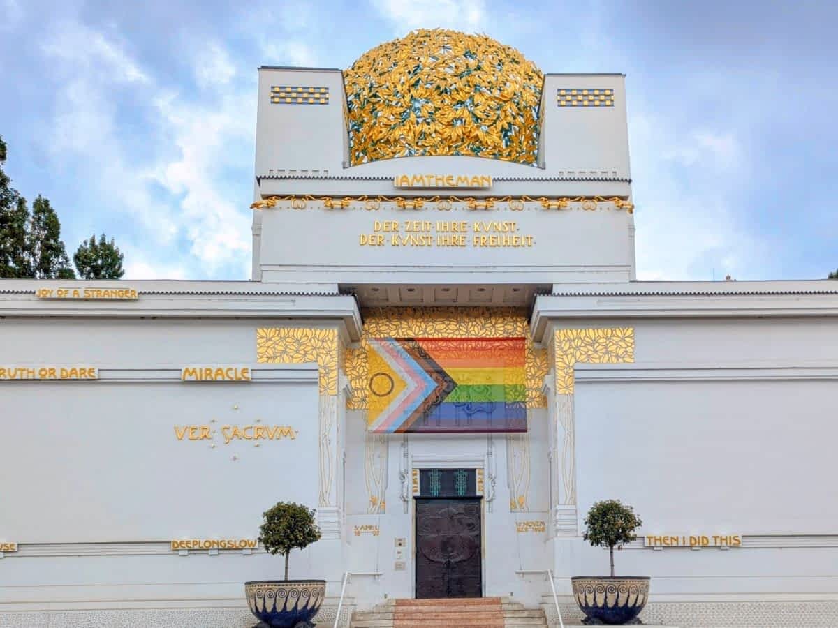 Frontansicht des Secessionsgebäudes in Wien mit markanter goldener Kuppel aus Blättermotiven und kunstvoller Fassadeninschrift.