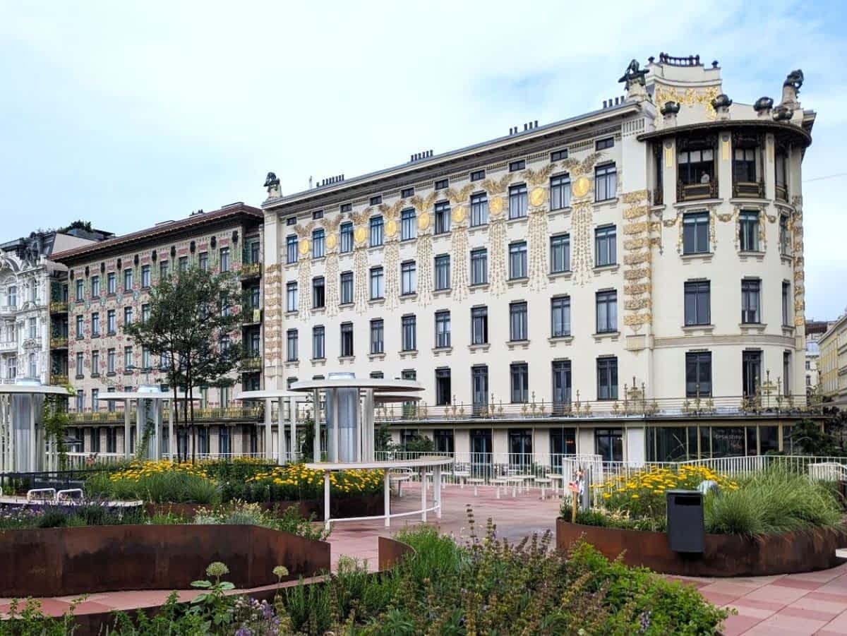 Das Wienzeile-Gebäude 38-40 in Wien im Jugendstil, mit seiner goldenen Ornamentik, vor einem strahlend blauen Himmel.